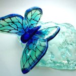 Vlinder van glas in blauw/groene tinten op 'steen' van helder reliëfglas - BxHxD 30x12x22 cm € 249,-